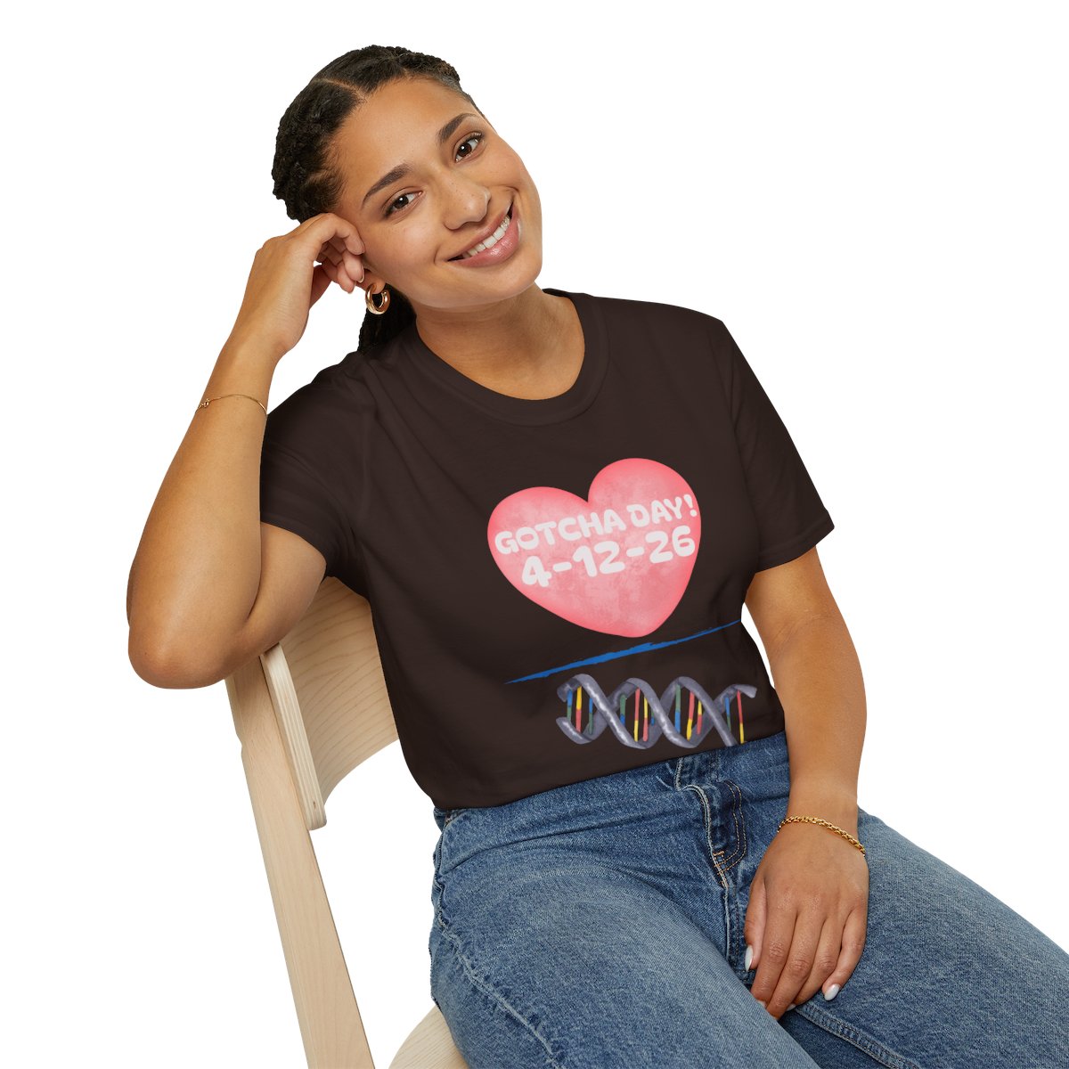 Person sitting on a stool wearing a black T‑shirt with a pink heart graphic and printed text on the front.