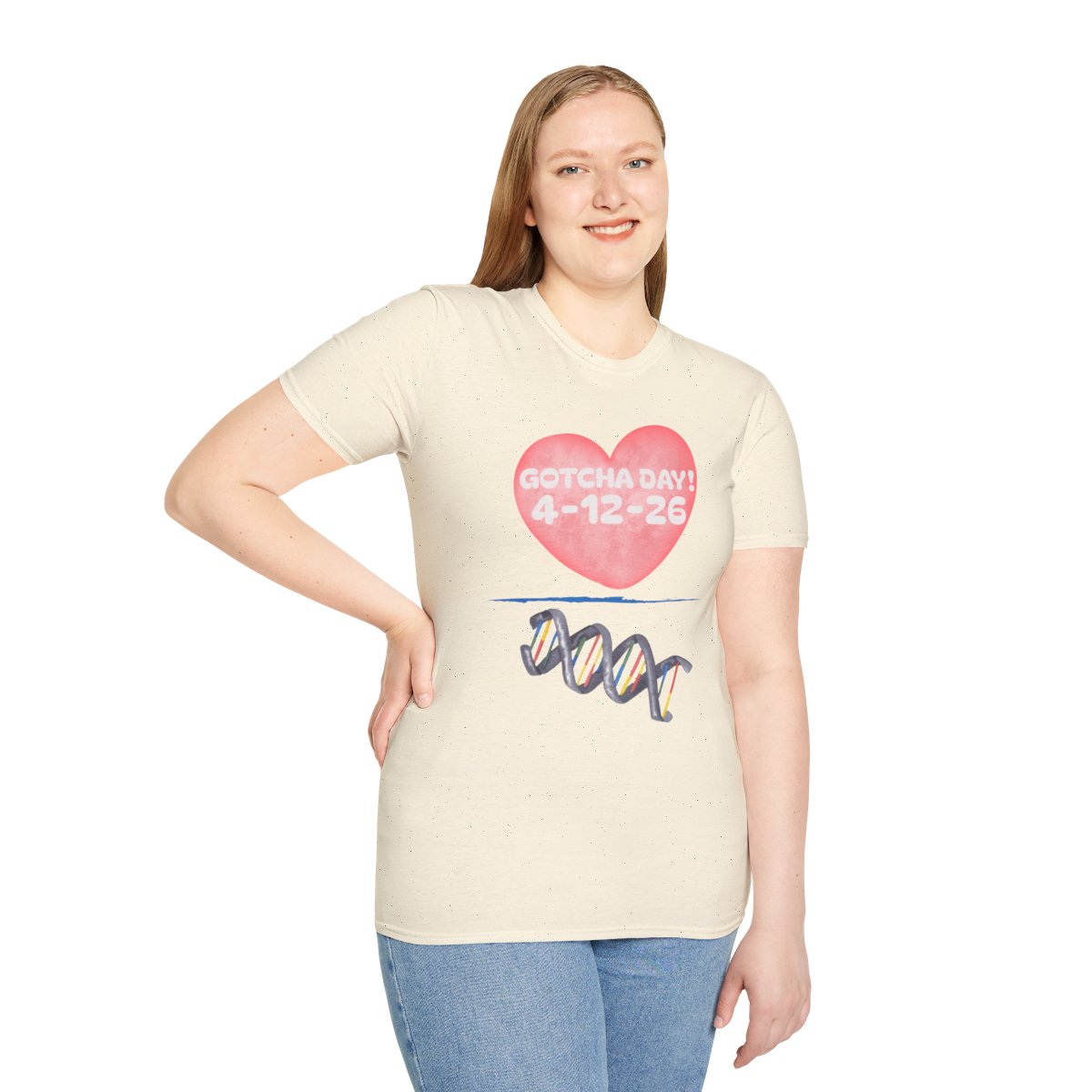 Person standing against a white background wearing a light-colored T‑shirt with a pink heart graphic and printed text.